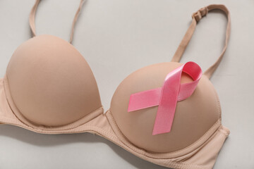 Bra with pink ribbon on grey background, closeup. Breast cancer awareness concept