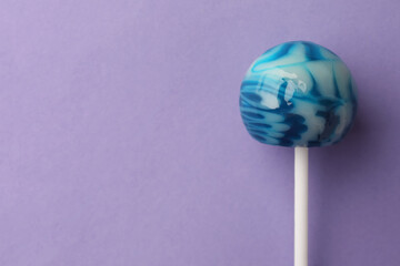 Tasty lollipop on violet background, top view. Space for text