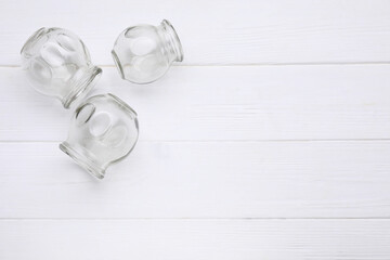 Glass cups on white wooden table, flat lay with space for text. Cupping therapy