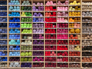 Shop shelf with multicolored yarn for knitting. Sale of goods for creativity and needlework. Bright colorful earn balls full frame background