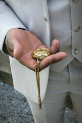 Fototapeta premium man holding gold pocket watch in beige suit
