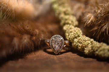pear shaped diamond bridal ring with pave laying on wooden floor against boho florals