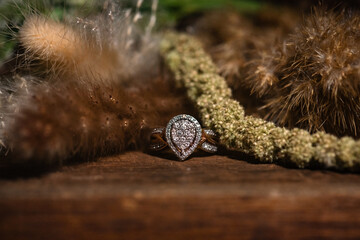 pear shaped diamond bridal ring with pave laying on wooden floor against boho florals