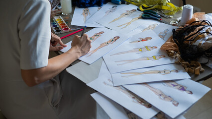 Faceless woman draws sketches of swimwear. Close-up of the hands of a fashion designer.