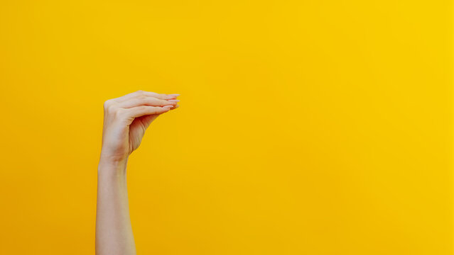 Hand theater. News advertisement. Female woman arm mouth gesture talking fun performance introducing sensation isolated on yellow background empty space.