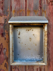 Metal box on red painted old wooden wall