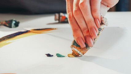 Drawing process. Artistic equipment. Unrecognizable woman painter hands squeezing paint out of tube creating picture in studio. © golubovy