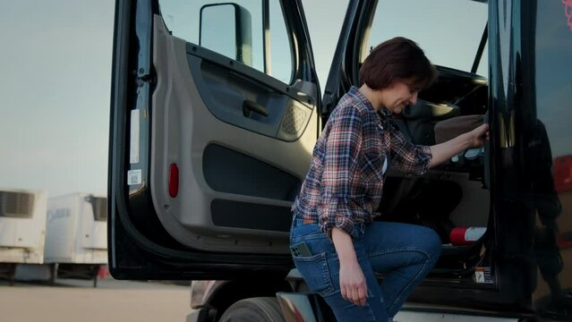A woman trucker stands in a semi truck. Day shot. Close up shot