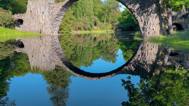 Devil's Bridge Rakotzbrucke in the Rhododendron Palace Landscape Park Kromlau, Lake Rakotz, Saxony, Germany. High quality 4k footage
