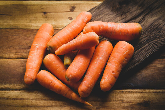 Fresh carrots on worn wood, close-up image
