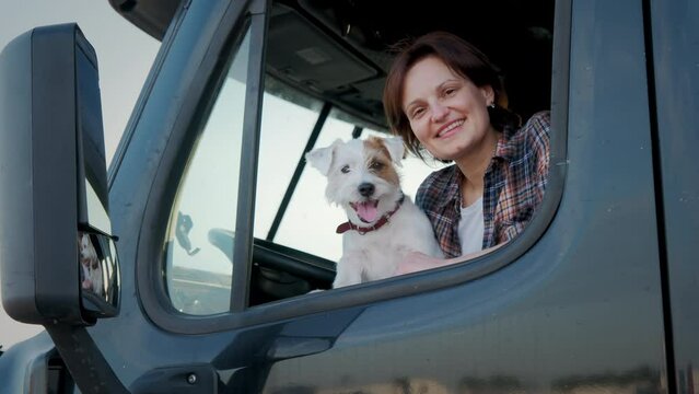 A woman trucker sit in a semi truck along with the dog. Close up