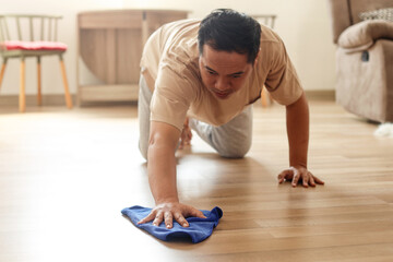 Asian man wiping parquet floor. Husband housekeeping and cleaning concept. 