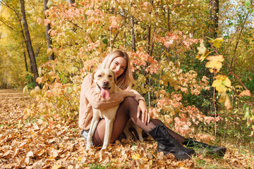 A young woman walking with her beloved labrador dog in autumn park.
