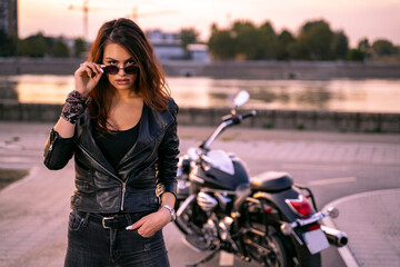 Confident biker woman looking directly at camera, enjoying sunset by the river view 