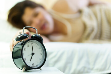 Asian oversize fat woman sleep on the bed in morning, during the time, an alarm clock is alarming...