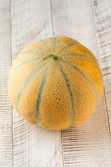 Ripe juicy round melon on a light wooden background. Fruit