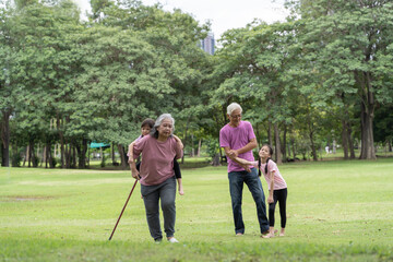 Senior couple with granddaughter on a walk outside in nature. Seniors with granddaughter, summer day. People walking on grass.