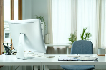 Comfortable workplace with computer monitor, office supplies and document on white table.