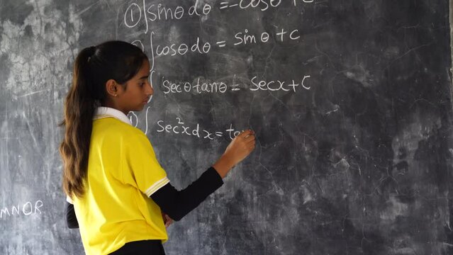 Happy Indian school girl child standing in front of black chalkboard background. Education Concept or Back to School