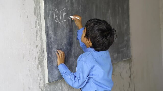 Asian school boy wearing uniform. Portrait of happy cute little indian boy in school uniform, Adorable elementary kid showing black board. child education concept. rural india.