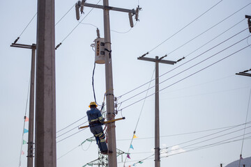 Liniero electricista ingeniero trabajando trepando un poste para reparar y dar mantenimiento a una linea eléctrica y un transformador 
