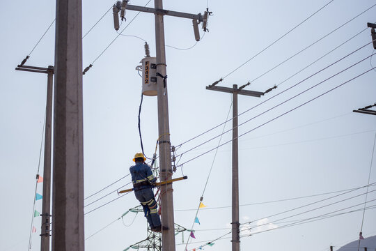 Liniero electricista ingeniero trabajando trepando un poste para reparar y dar mantenimiento a una linea el&eacute;ctrica y un transformador 
