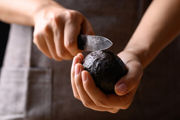 Ripe hass avocado fruit with hand holding knife and cutting