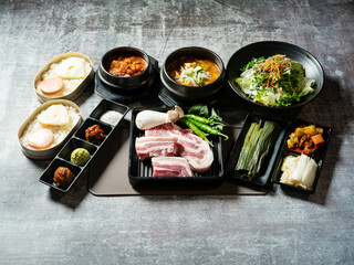 A set of various parts of raw pork, side dishes, and stew