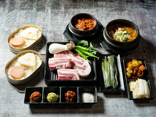 A set of various parts of raw pork, side dishes, and stew