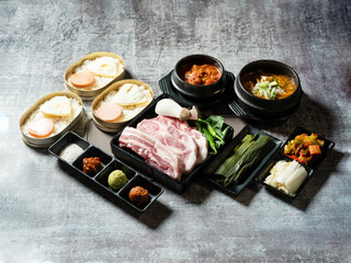 A set of various parts of raw pork, side dishes, and stew