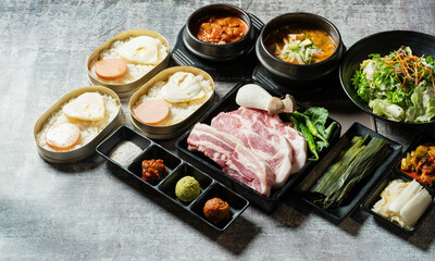 A set of various parts of raw pork, side dishes, and stew