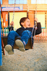 vertical photo of a very happy latin child playing on a park swing in la paz bolivia, latin america