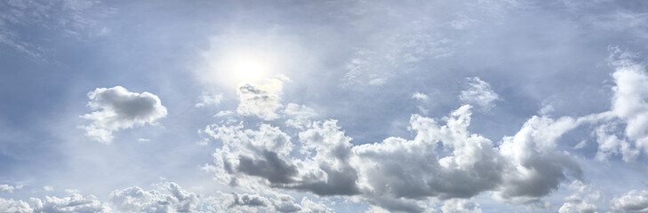summer blue sky with beautiful fluffy cumulus clouds and bright sun. panoramic view.