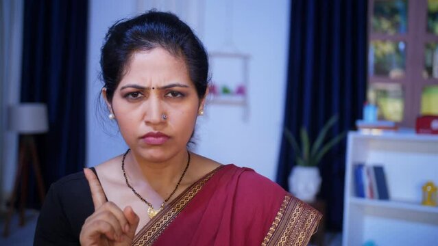 A middle-aged female shushing with a finger on her lips while looking towards the camera - angry female  scolding . An Indian woman wearing a traditional Saree gesturing shh - secrecy or silence  a...