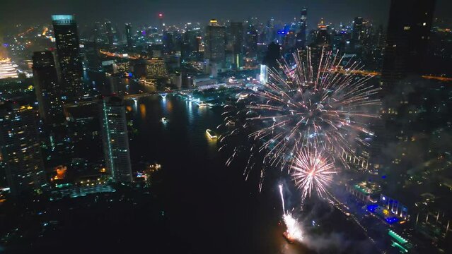 Aerial drone point of view Multi colors Fireworks Displays over the Cityscape and Skyscraper Celebrate Night Lights, river and Bangkok bridge
