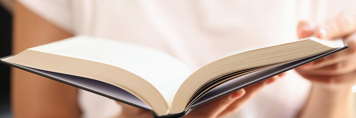 Woman holding open book in her hands close up, shallow depth of field.