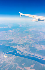 Aerial view from airplane window above green ground. View from the airplane window with beautiful clouds at sunrise