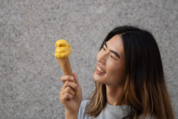 Side view of cheerful asian gay man looking at yellow icecream with happy face and copy space
