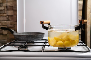 Boiling potato in transparent glass pot