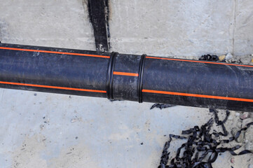 Soldered joint of black plastic pipe for soil heating, against the background of concrete and...
