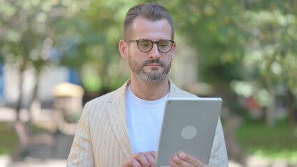 Middle Aged Man using Tablet Outdoor