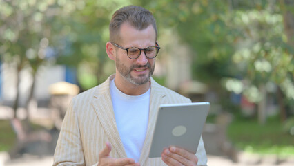 Middle Aged Man Upset by Loss on Tablet Outdoor