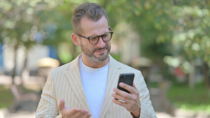 Fototapeta premium Upset Middle Aged Man get Shocked on Smartphone Outdoor