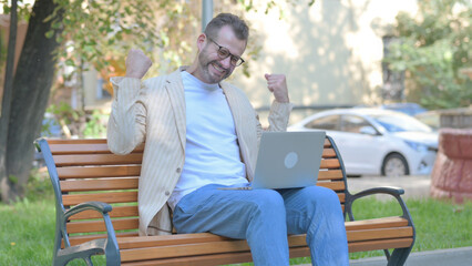 Excited Modern Casual Man Celebrating Success on Laptop Outdoor