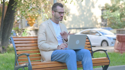 Fototapeta premium Online Video Chat by Modern Casual Man on Laptop Outdoor