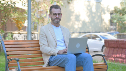 Fototapeta premium Rejecting Modern Casual Man Working on Laptop Outdoor