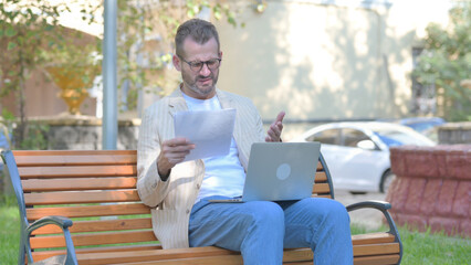 Fototapeta premium Modern Casual Man Celebrating while Working on Laptop and Documents Outdoor
