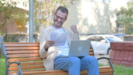 Fototapeta premium Modern Casual Man Working on Documents and Laptop Outdoor