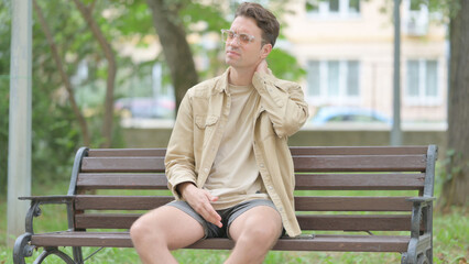 Tired Casual Young Man Sitting Outdoor with Neck Pain