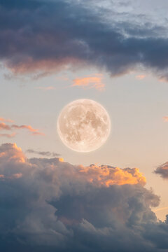 Big full moon among bright clouds at sunset